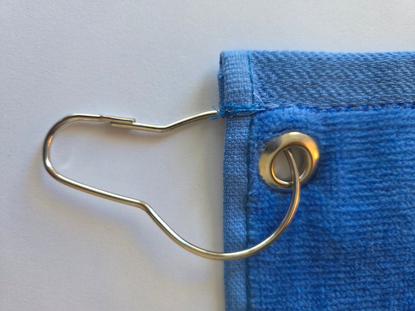 Close-up of a blue denim fabric with a metal clip on a white background