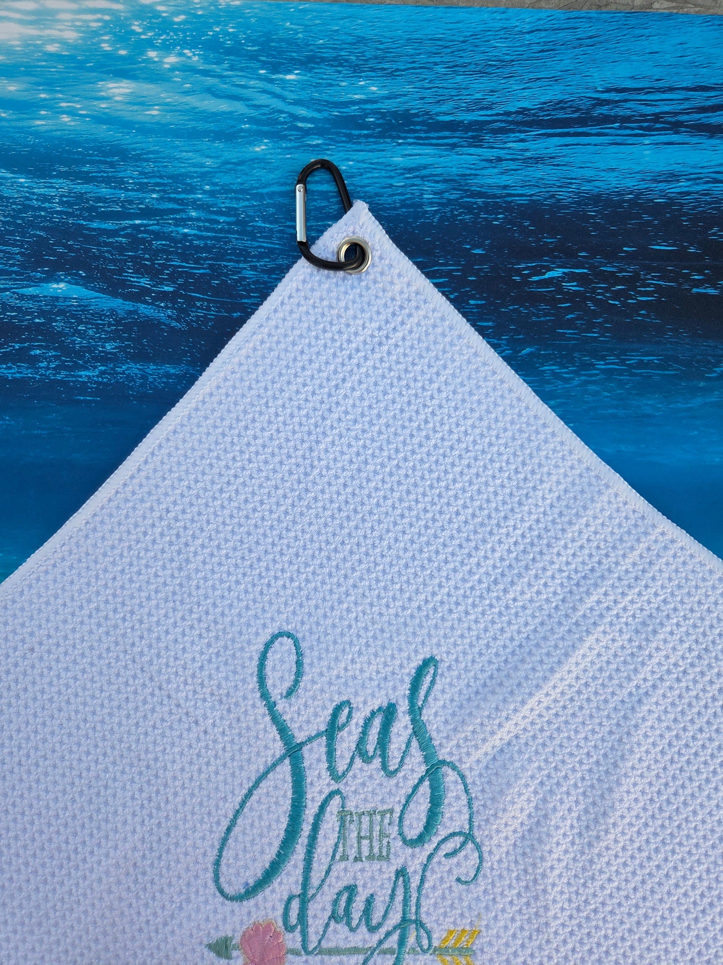Light blue towel with floral design and text on a textured blue surface