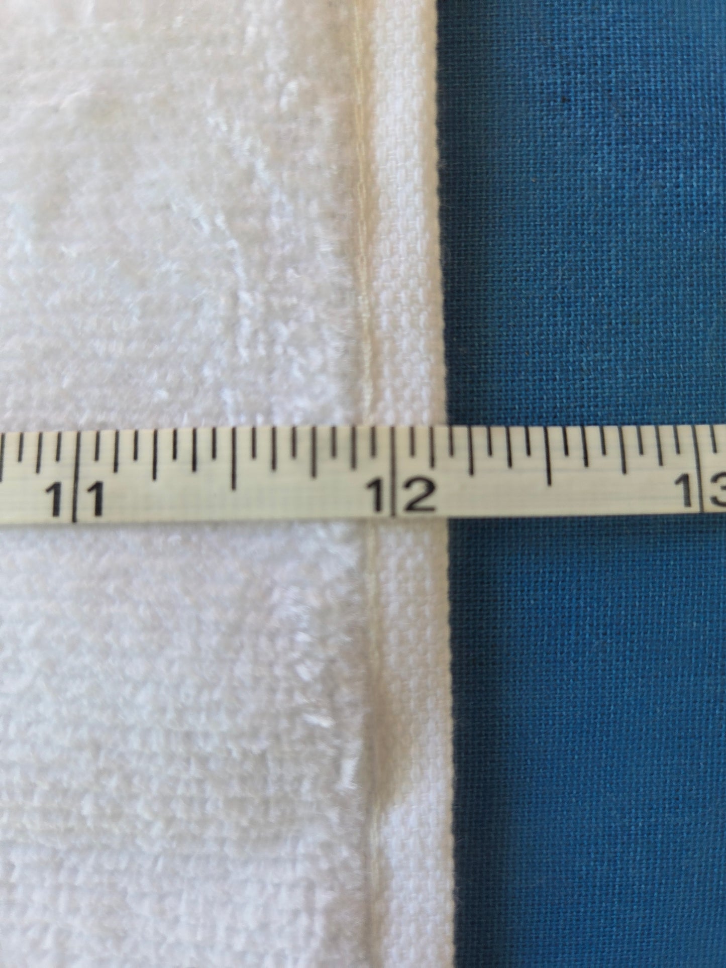 Measurement of fabric width using a ruler on a blue and beige fabric background