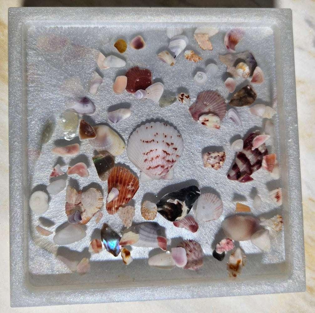 Resin coaster with seashell accents on sand backdrop, coastal décor