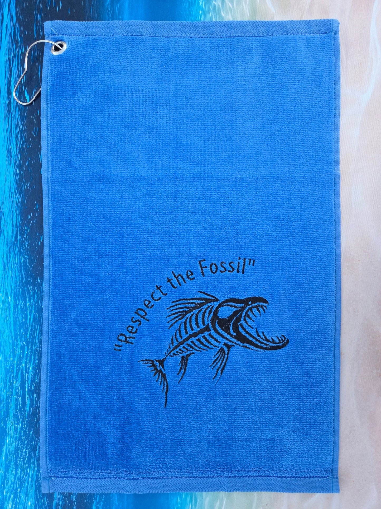 Blue towel with a fish skeleton design and text on a water-themed background