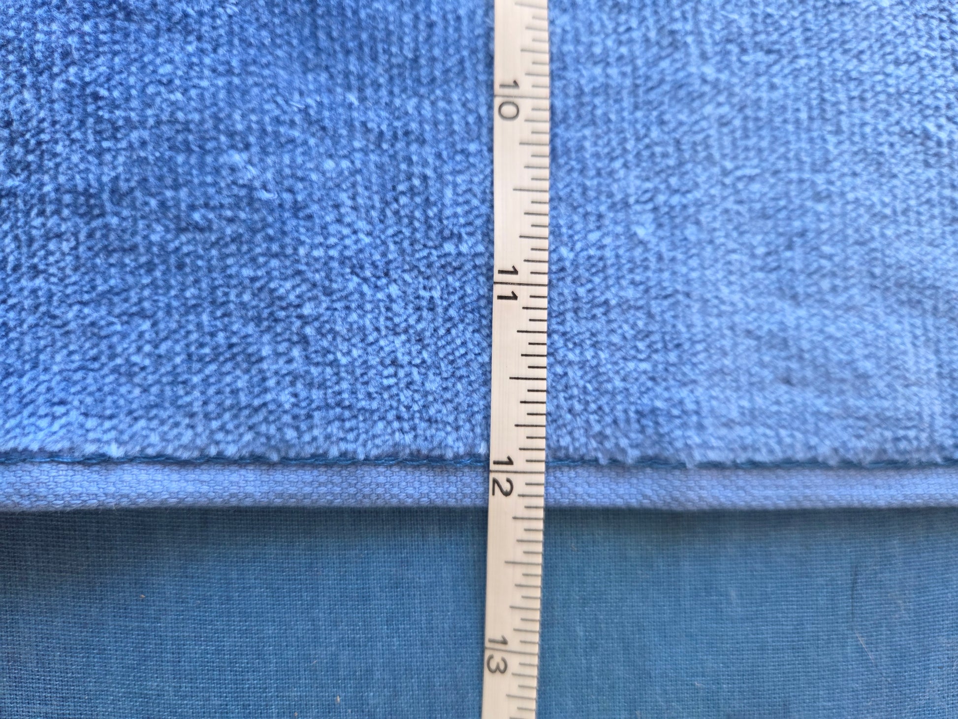 Roll of blue fabric with a measuring tape indicating dimensions
