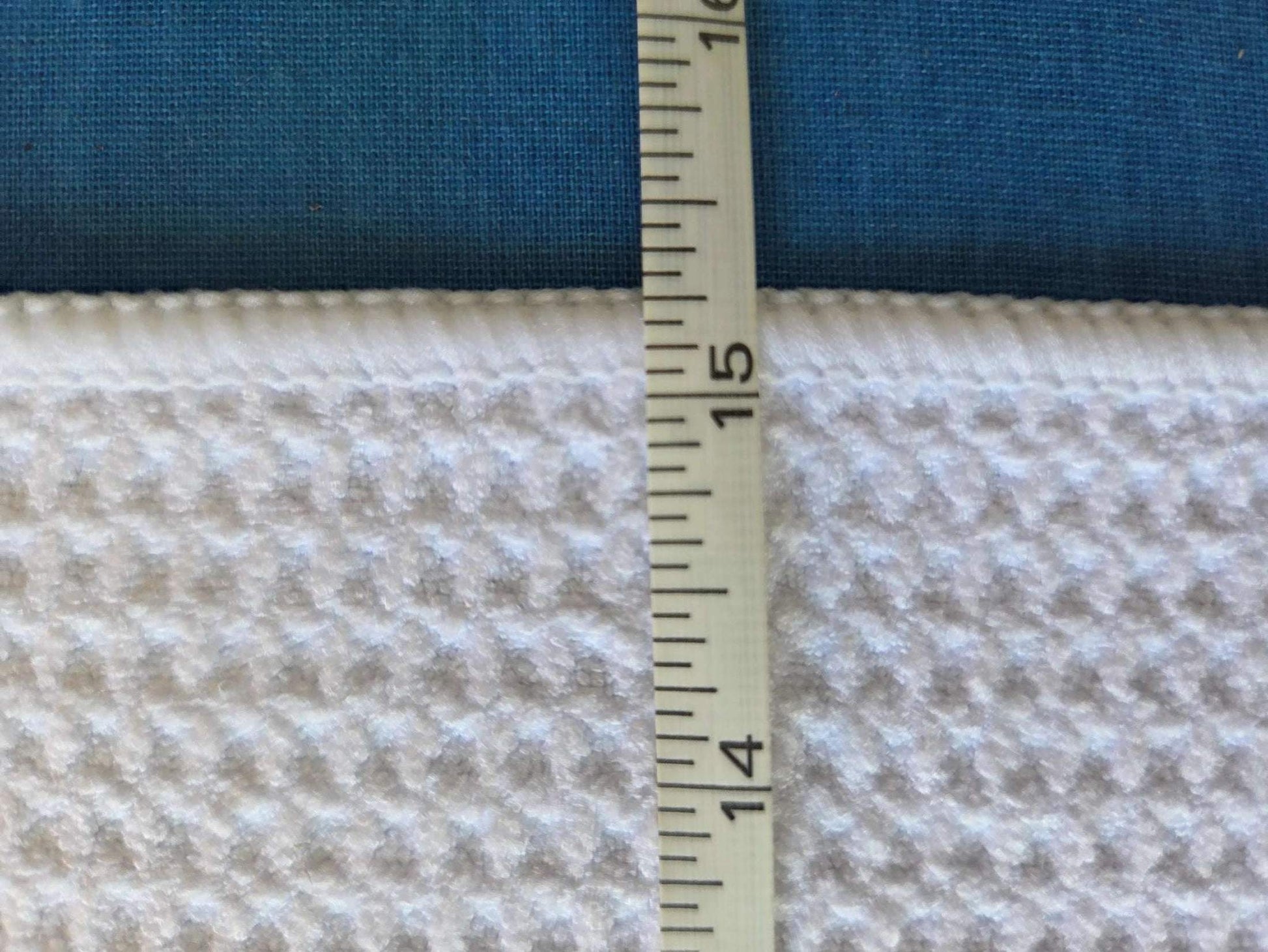 Two fabrics, one blue and one beige with a pattern, with a ruler showing measurements.