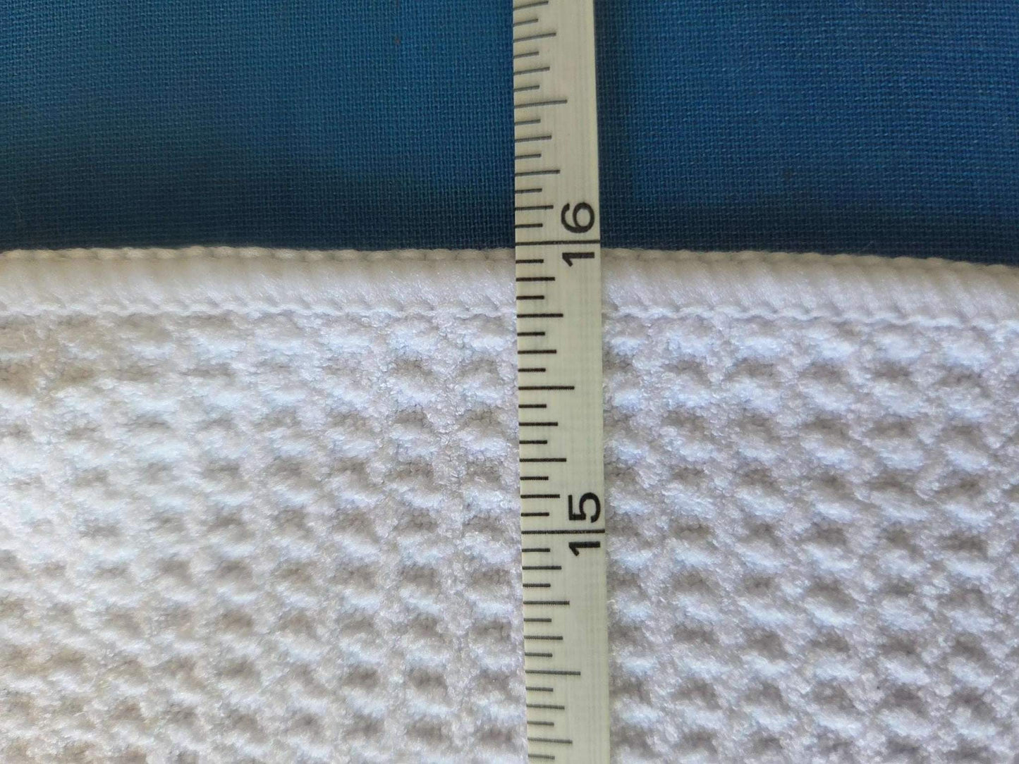 Measurement of fabric thickness with a ruler on a blue and beige textured fabric background