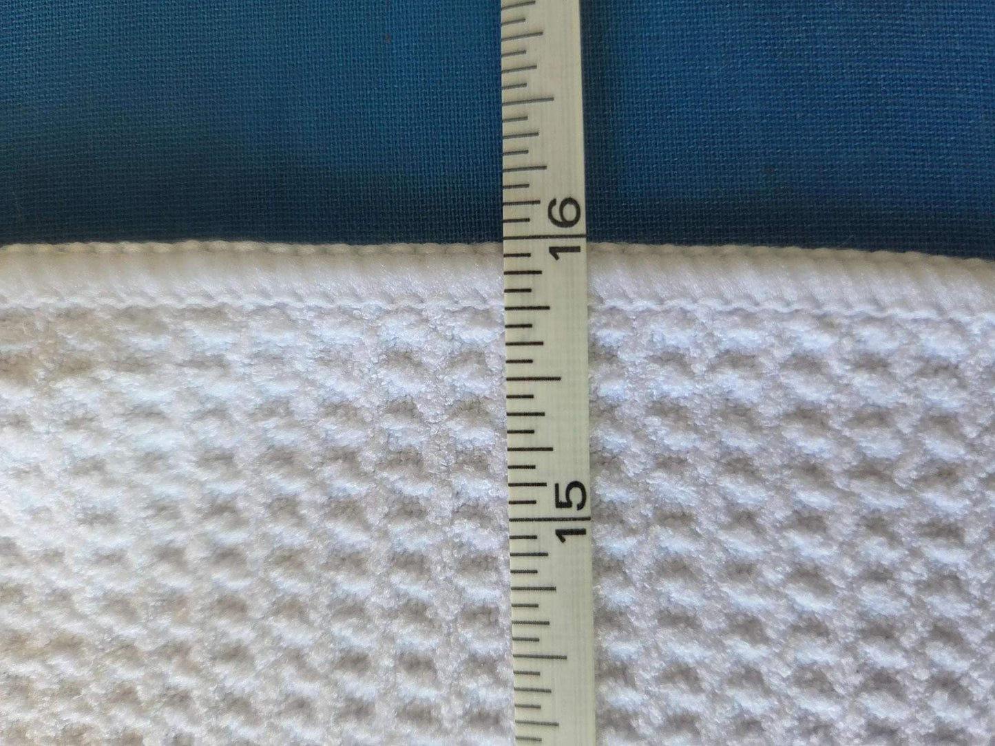 Measurement of fabric thickness with a ruler on a blue and beige textured fabric background