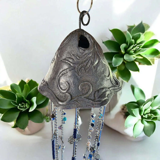 Silver and Blue windchime with plants in background