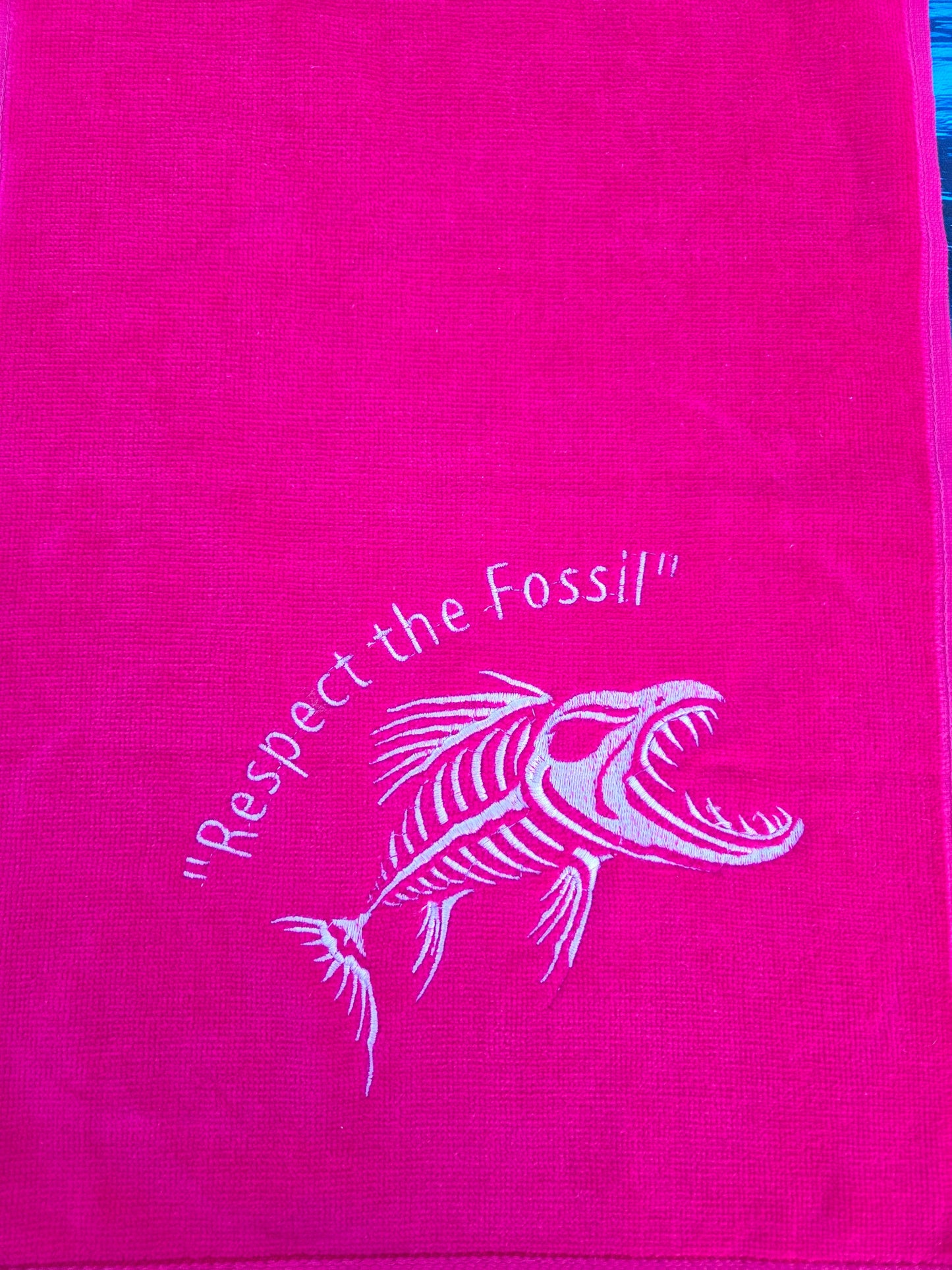 Pink towel with white fossil design and text on a pink background