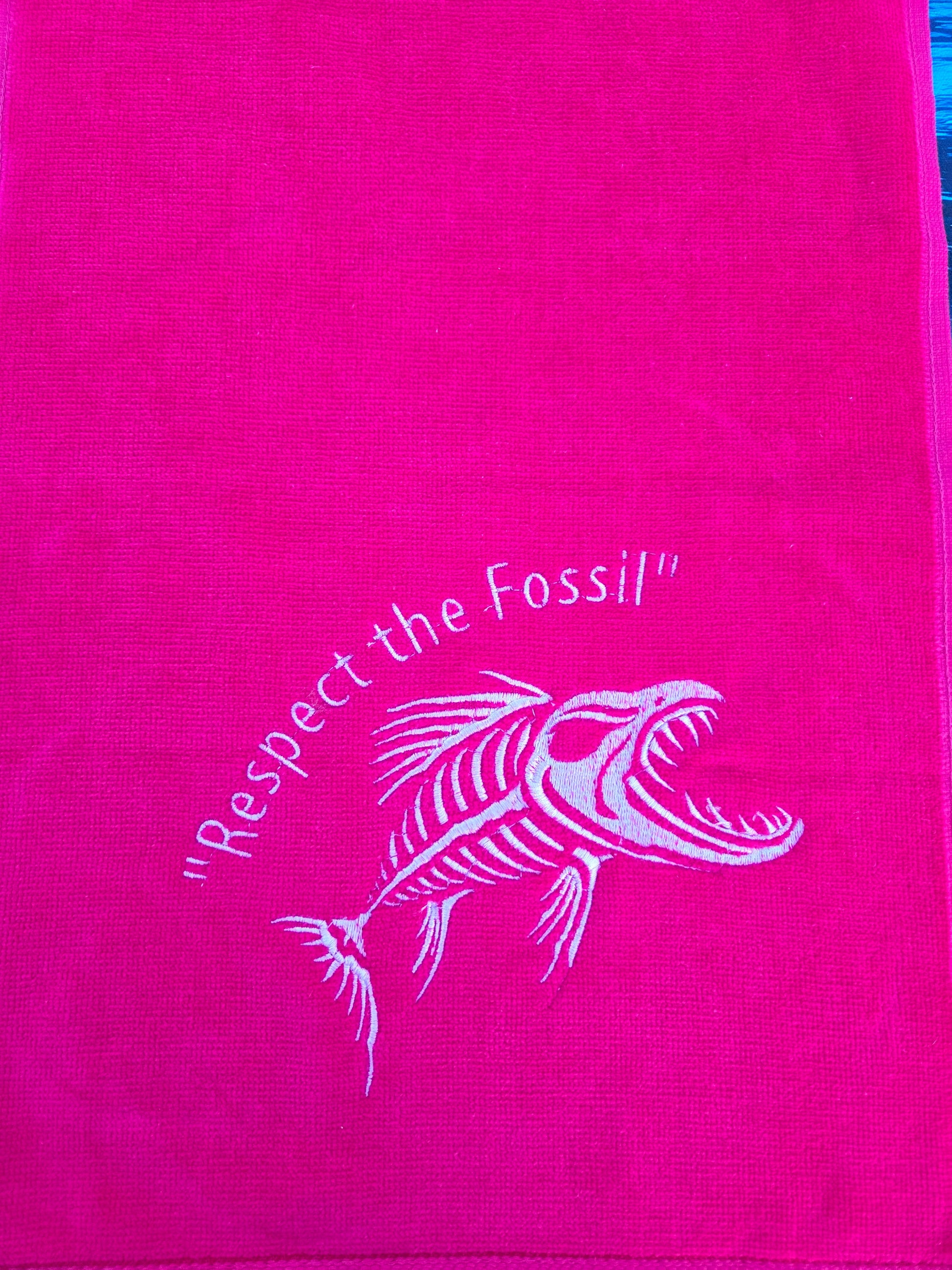 Pink towel with white fossil design and text on a pink background