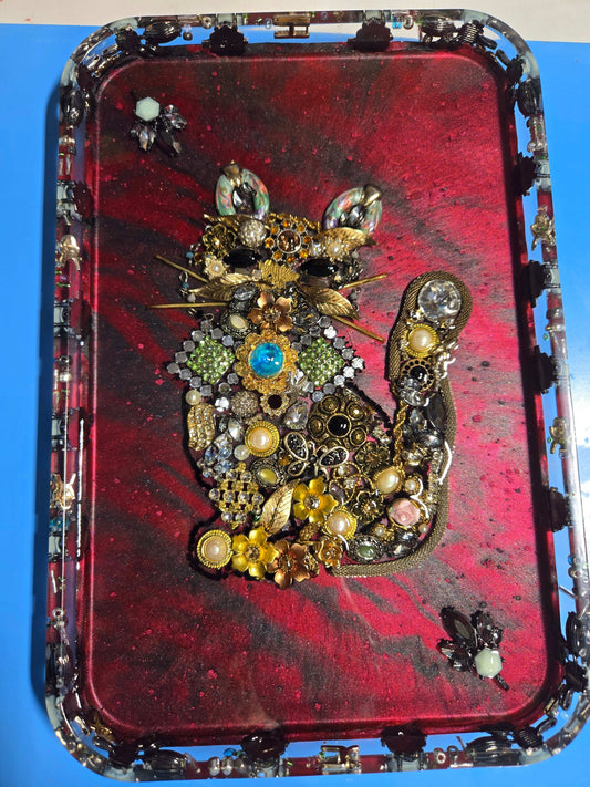 Upcycled vintage jewelry cat resin tray on deep red background, with brooches, pearls and watch parts