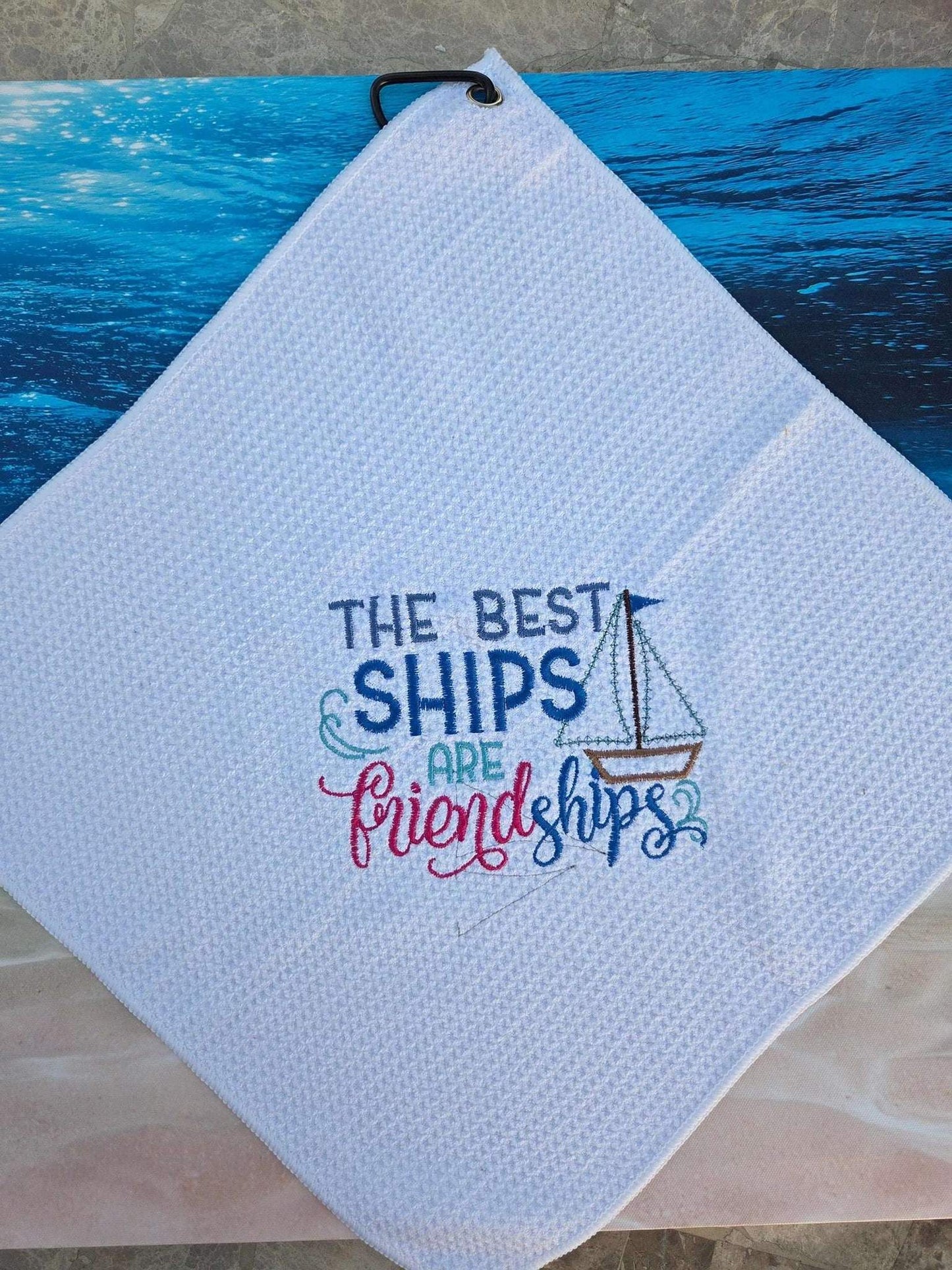 White towel with embroidered text and design on a blue surface